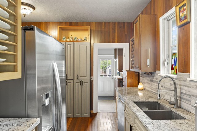 4524 Post St, Jacksonville, FL 32205 - kitchen featuring a sink, stainless steel appliances, tasteful backsplash, wood walls, and light stone countertops