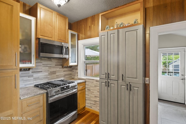 4524 Post St, Jacksonville, FL 32205 - kitchen with stainless steel appliances, backsplash, glass insert cabinets, light stone counters, and open shelves