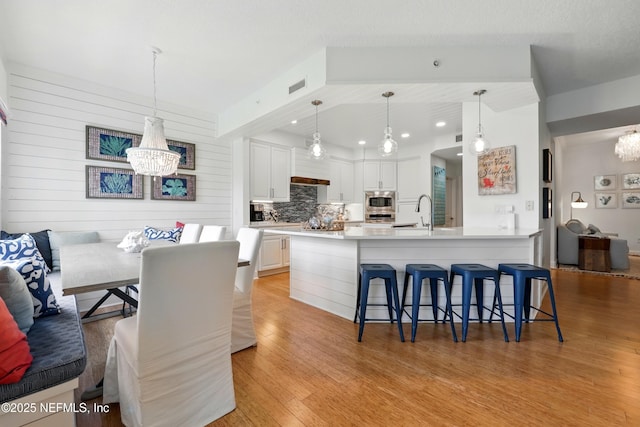 310 S Ocean Grande Dr Unit 205, Ponte Vedra Beach, FL 32082 - kitchen featuring a chandelier, stainless steel appliances, decorative backsplash, a kitchen breakfast bar, and light wood-type flooring