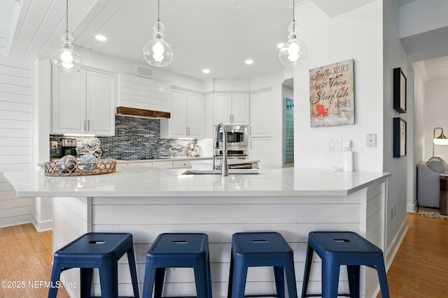 310 S Ocean Grande Dr Unit 205, Ponte Vedra Beach, FL 32082 - kitchen with stainless steel microwave, light wood-type flooring, white cabinetry, backsplash, and recessed lighting
