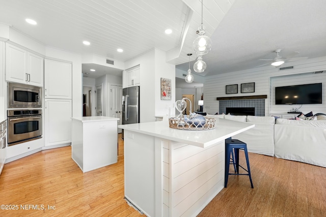 310 S Ocean Grande Dr Unit 205, Ponte Vedra Beach, FL 32082 - kitchen featuring stainless steel appliances, a center island, a ceiling fan, light wood finished floors, and a fireplace
