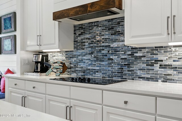 310 S Ocean Grande Dr Unit 205, Ponte Vedra Beach, FL 32082 - kitchen with decorative backsplash, premium range hood, light countertops, black electric cooktop, and white cabinets