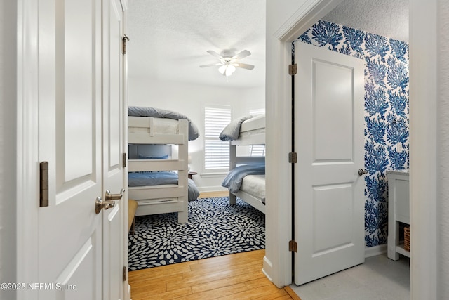 310 S Ocean Grande Dr Unit 205, Ponte Vedra Beach, FL 32082 - bedroom featuring wood finished floors, a ceiling fan, a textured ceiling, and wallpapered walls
