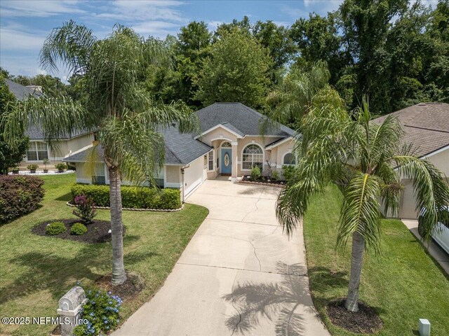 2888 Majestic Oaks Ln, Green Cove Springs, FL 32043 - view of front facade with concrete driveway, an attached garage, stucco siding, a front lawn, and a shingled roof
