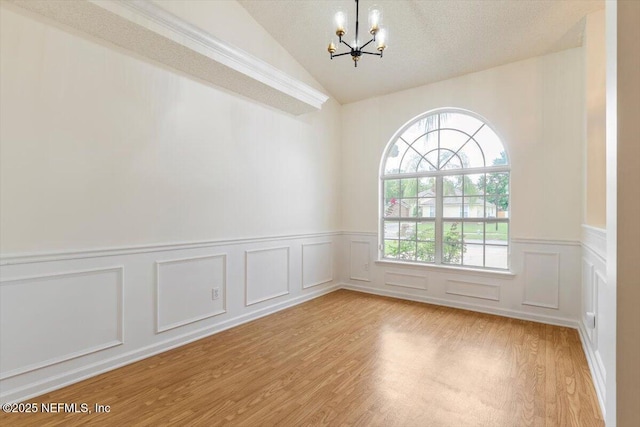 2888 Majestic Oaks Ln, Green Cove Springs, FL 32043 - empty room featuring a chandelier, lofted ceiling, light wood finished floors, wainscoting, and a decorative wall