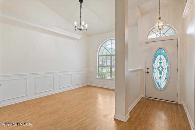2888 Majestic Oaks Ln, Green Cove Springs, FL 32043 - foyer entrance featuring a chandelier, wood finished floors, a wainscoted wall, a textured ceiling, and high vaulted ceiling