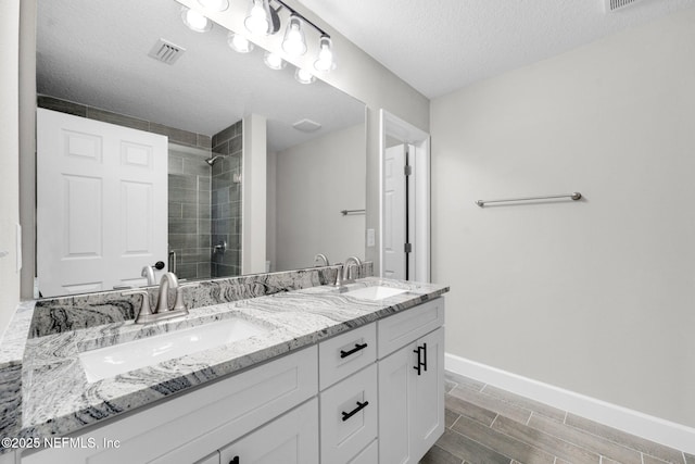 1731 W 28th St, Jacksonville, FL 32209 - bathroom with double vanity, tiled shower, baseboards, and a textured ceiling