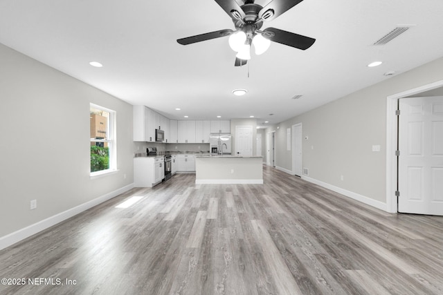 1731 W 28th St, Jacksonville, FL 32209 - unfurnished living room featuring light wood finished floors, baseboards, ceiling fan, recessed lighting, and a sink