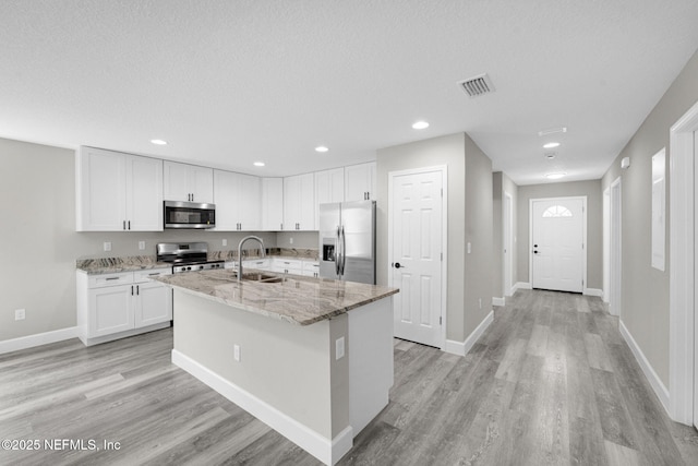 1731 W 28th St, Jacksonville, FL 32209 - kitchen featuring stainless steel appliances, white cabinetry, light wood-style floors, a center island with sink, and recessed lighting