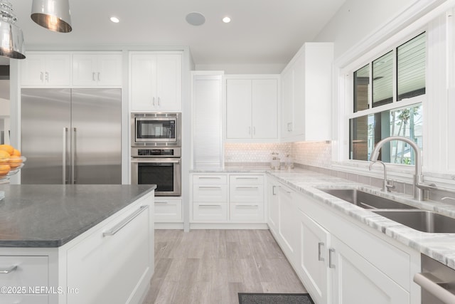 365 8th St, Atlantic Beach, FL 32233 - kitchen with built in appliances, recessed lighting, light wood-style flooring, tasteful backsplash, and light stone countertops