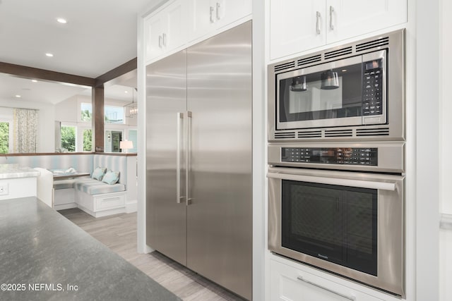 365 8th St, Atlantic Beach, FL 32233 - kitchen featuring built in appliances, white cabinets, light wood-style floors, recessed lighting, and beamed ceiling