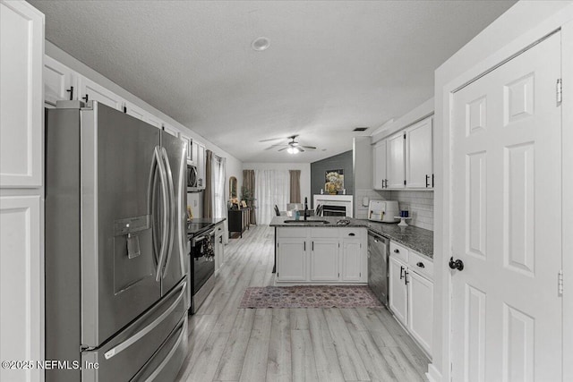 11214 Bentley Trace Ln E, Jacksonville, FL 32257 - kitchen featuring stainless steel appliances, open floor plan, light wood-type flooring, white cabinets, and a textured ceiling
