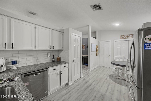 11214 Bentley Trace Ln E, Jacksonville, FL 32257 - kitchen featuring stainless steel appliances, lofted ceiling, white cabinets, tasteful backsplash, and light wood-type flooring