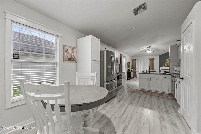 11214 Bentley Trace Ln E, Jacksonville, FL 32257 - kitchen featuring appliances with stainless steel finishes, a peninsula, light wood-style flooring, dark countertops, and a ceiling fan