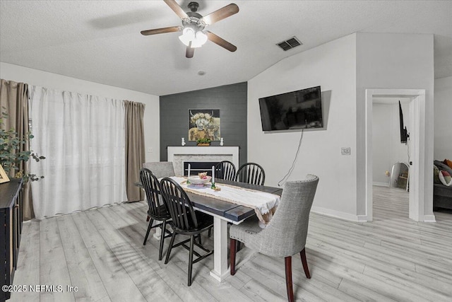 11214 Bentley Trace Ln E, Jacksonville, FL 32257 - dining room featuring vaulted ceiling, light wood finished floors, a ceiling fan, a fireplace, and a textured ceiling