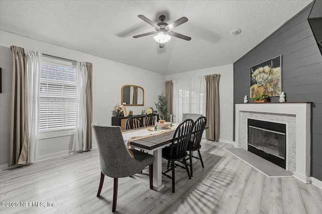 11214 Bentley Trace Ln E, Jacksonville, FL 32257 - dining room featuring a textured ceiling, lofted ceiling, light wood-type flooring, ceiling fan, and a glass covered fireplace