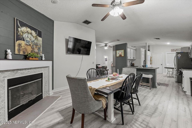 11214 Bentley Trace Ln E, Jacksonville, FL 32257 - dining area with a ceiling fan, vaulted ceiling, light wood finished floors, a fireplace with flush hearth, and a textured ceiling