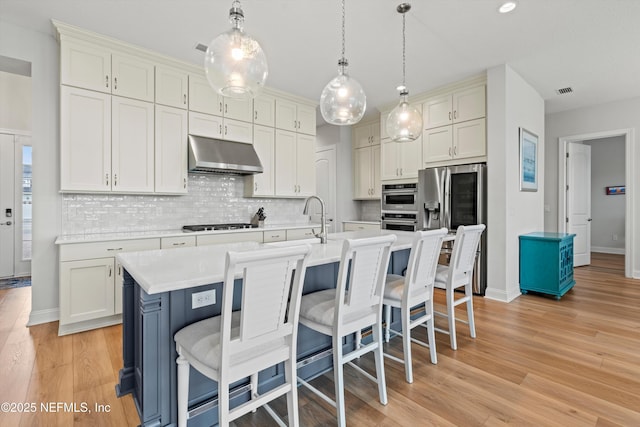 46 Hydrilla Ct, Saint Augustine, FL 32095 - kitchen with under cabinet range hood, light countertops, decorative backsplash, and a breakfast bar area