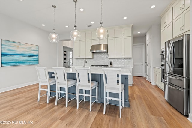 46 Hydrilla Ct, Saint Augustine, FL 32095 - kitchen with appliances with stainless steel finishes, under cabinet range hood, light countertops, light wood-type flooring, and tasteful backsplash