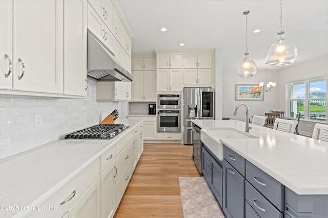 46 Hydrilla Ct, Saint Augustine, FL 32095 - kitchen with appliances with stainless steel finishes, gray cabinetry, light countertops, under cabinet range hood, and a chandelier