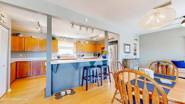 23 Moody Dr, Palm Coast, FL 32137 - kitchen featuring light countertops, light wood-type flooring, a breakfast bar area, brown cabinets, and appliances with stainless steel finishes