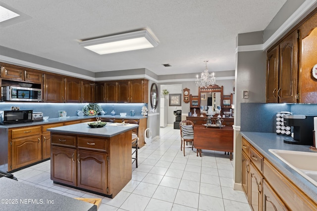 2364 Smullian Trl S, Jacksonville, FL 32217 - kitchen featuring stainless steel microwave, black microwave, a chandelier, light tile patterned floors, and a kitchen island