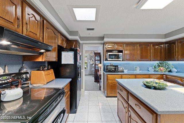 2364 Smullian Trl S, Jacksonville, FL 32217 - kitchen featuring electric range oven, stainless steel microwave, range hood, light countertops, and brown cabinetry