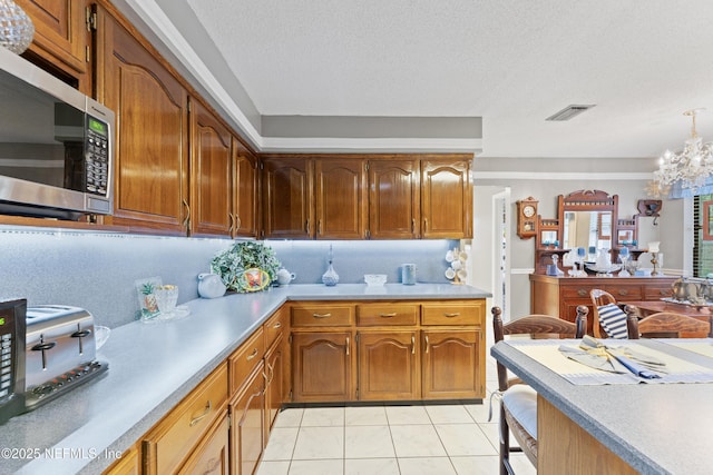 2364 Smullian Trl S, Jacksonville, FL 32217 - kitchen featuring stainless steel microwave, light countertops, light tile patterned flooring, a chandelier, and brown cabinetry