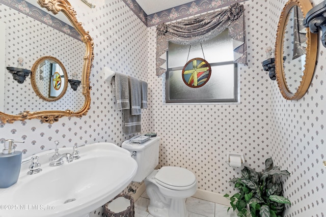 2364 Smullian Trl S, Jacksonville, FL 32217 - bathroom with wallpapered walls, a sink, toilet, marble look tile flooring, and baseboards