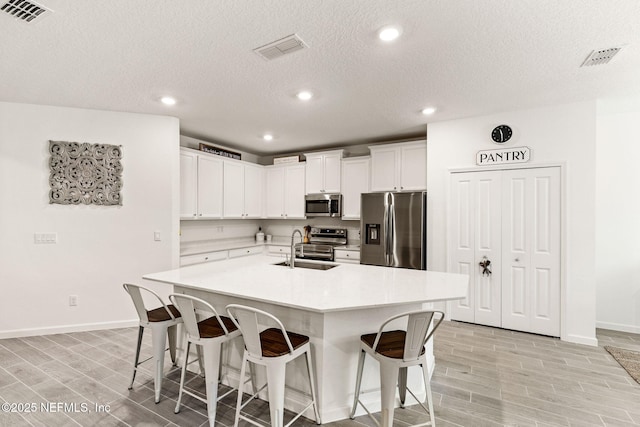 85600 Stonehurst Pkwy, Fernandina Beach, FL 32034 - kitchen with appliances with stainless steel finishes, baseboards, a kitchen breakfast bar, a sink, and wood finish floors