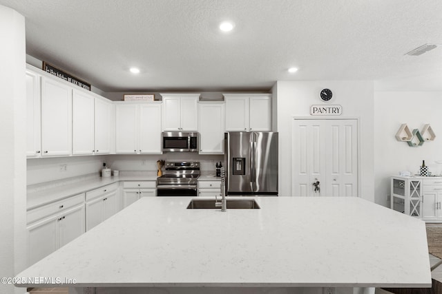 85600 Stonehurst Pkwy, Fernandina Beach, FL 32034 - kitchen with stainless steel appliances, a sink, a large island with sink, white cabinets, and recessed lighting