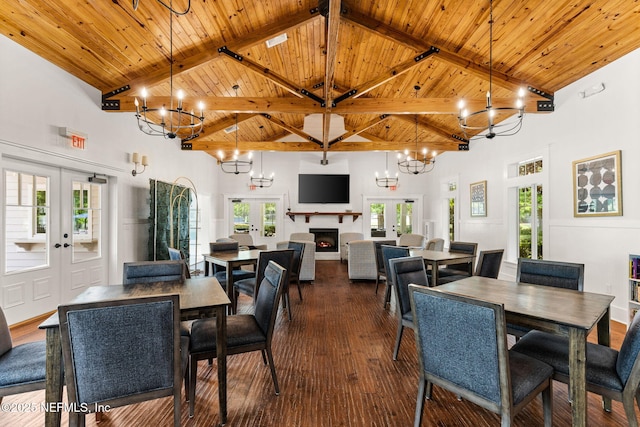 85600 Stonehurst Pkwy, Fernandina Beach, FL 32034 - dining space with french doors, high vaulted ceiling, a chandelier, wood ceiling with exposed beams, and a lit fireplace