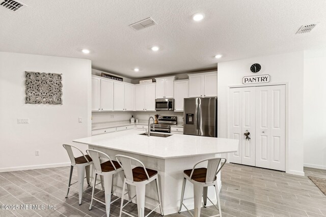 85600 Stonehurst Pkwy, Fernandina Beach, FL 32034 - kitchen with appliances with stainless steel finishes, baseboards, a kitchen bar, wood tiled floors, and a sink