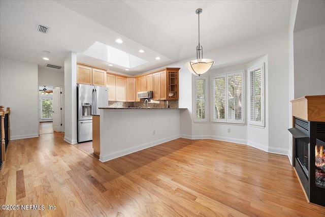 2049 Seminole Rd, Atlantic Beach, FL 32233 - kitchen featuring appliances with stainless steel finishes, a lit fireplace, a skylight, glass insert cabinets, and decorative backsplash