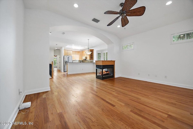 2049 Seminole Rd, Atlantic Beach, FL 32233 - unfurnished living room with arched walkways, ceiling fan, a multi sided fireplace, light wood-style floors, and recessed lighting