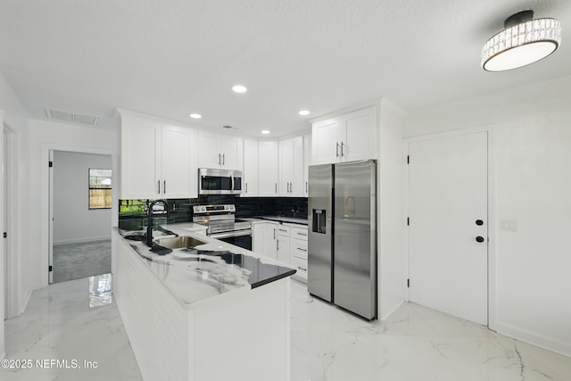 494 Acacia St, Saint Augustine Beach, FL 32080 - kitchen featuring appliances with stainless steel finishes, a sink, backsplash, white cabinets, and a peninsula
