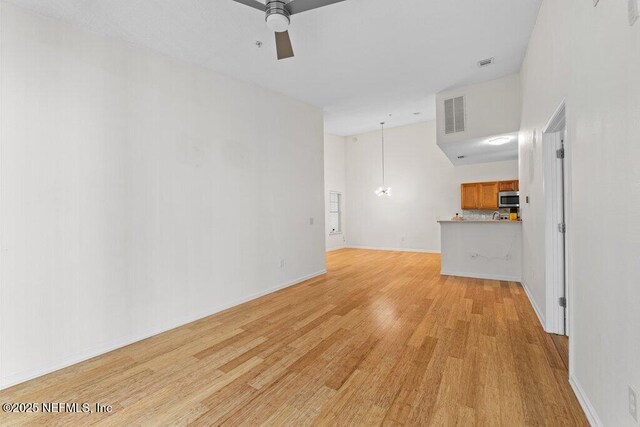 5006 Key Lime Dr Unit 306, Jacksonville, FL 32256 - unfurnished living room featuring light wood finished floors, ceiling fan, a towering ceiling, a chandelier, and baseboards