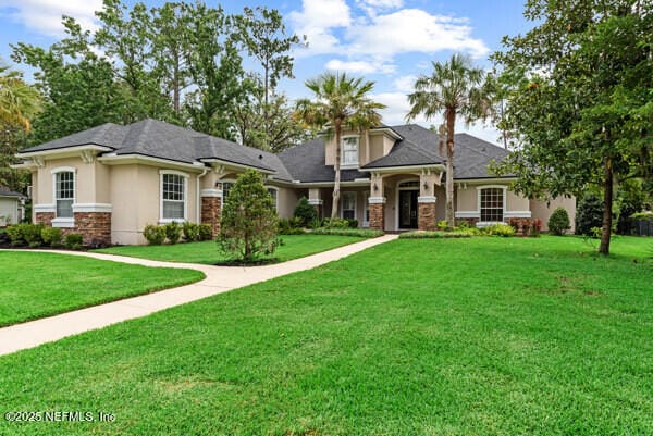 1821 Wind Ridge Ct, Fleming Island, FL 32003 - view of front facade featuring stucco siding, stone siding, and a front lawn