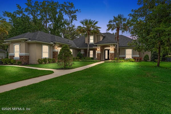1821 Wind Ridge Ct, Fleming Island, FL 32003 - view of front of house featuring stucco siding, a yard, and stone siding