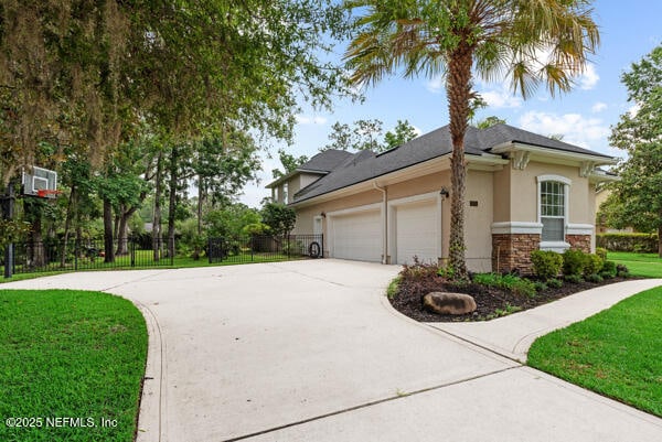 1821 Wind Ridge Ct, Fleming Island, FL 32003 - view of home's exterior with concrete driveway, stucco siding, an attached garage, and stone siding