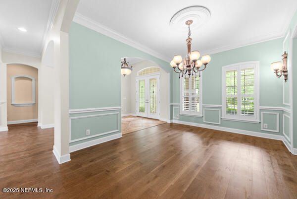 1821 Wind Ridge Ct, Fleming Island, FL 32003 - unfurnished dining area featuring a chandelier, arched walkways, ornamental molding, and wood finished floors