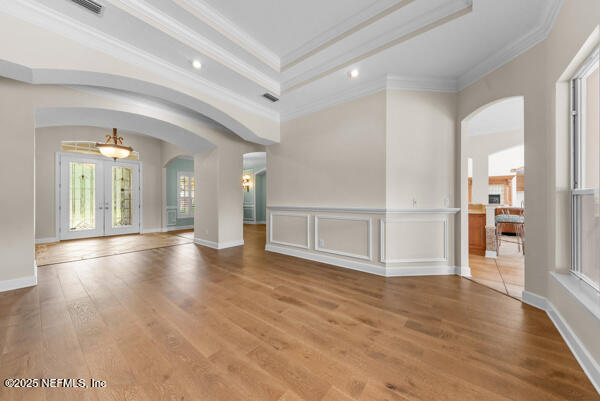 1821 Wind Ridge Ct, Fleming Island, FL 32003 - unfurnished living room with arched walkways, crown molding, french doors, wood finished floors, and a tray ceiling