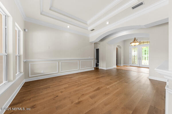 1821 Wind Ridge Ct, Fleming Island, FL 32003 - unfurnished room featuring arched walkways, a raised ceiling, ornamental molding, wood finished floors, and a chandelier