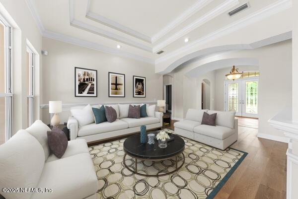 1821 Wind Ridge Ct, Fleming Island, FL 32003 - living room featuring arched walkways, crown molding, a raised ceiling, wood finished floors, and recessed lighting