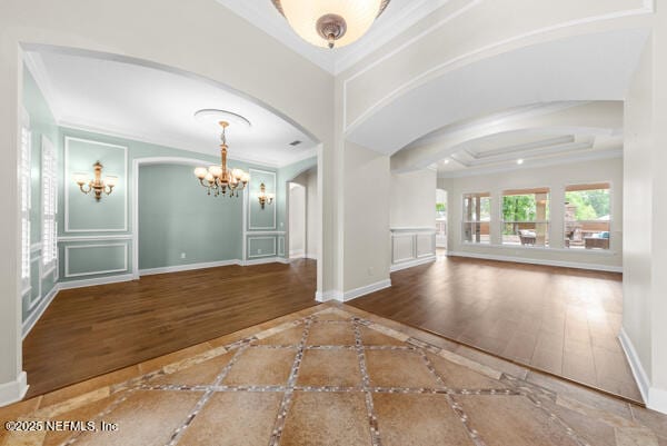 1821 Wind Ridge Ct, Fleming Island, FL 32003 - unfurnished living room featuring inlaid floor details, arched walkways, a chandelier, baseboards, and crown molding