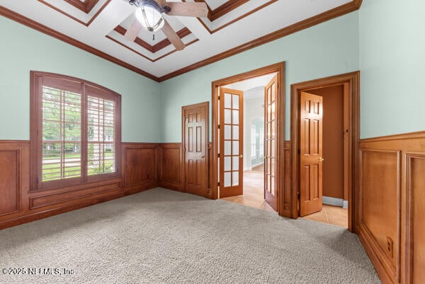 1821 Wind Ridge Ct, Fleming Island, FL 32003 - spare room featuring a wainscoted wall, ceiling fan, light carpet, crown molding, and french doors