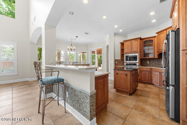 1821 Wind Ridge Ct, Fleming Island, FL 32003 - kitchen featuring appliances with stainless steel finishes, brown cabinetry, tasteful backsplash, arched walkways, and recessed lighting