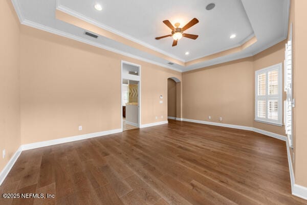 1821 Wind Ridge Ct, Fleming Island, FL 32003 - empty room with a tray ceiling, a ceiling fan, crown molding, wood finished floors, and arched walkways