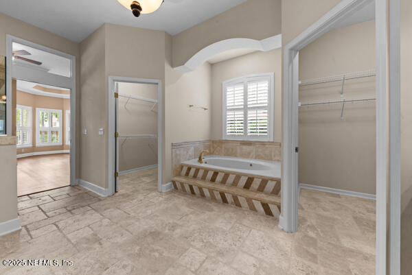 1821 Wind Ridge Ct, Fleming Island, FL 32003 - bathroom featuring a bath, a spacious closet, stone finish flooring, and baseboards
