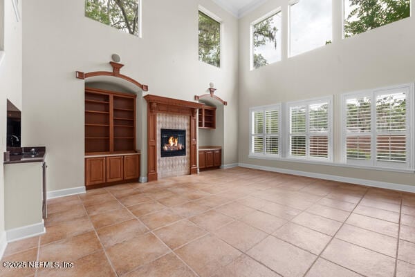 1821 Wind Ridge Ct, Fleming Island, FL 32003 - unfurnished living room with light tile patterned floors, a towering ceiling, a fireplace, plenty of natural light, and baseboards